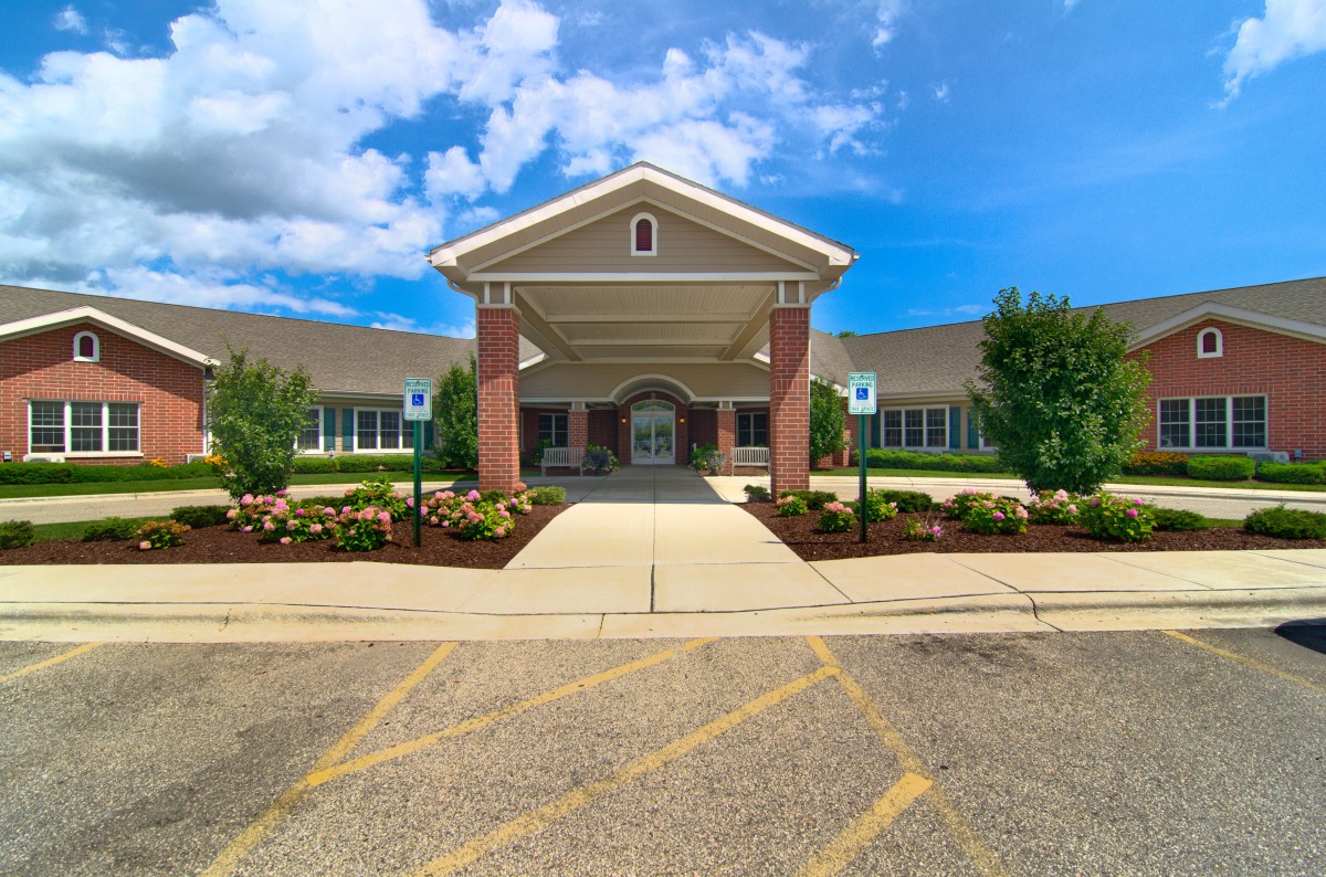 A well-maintained building entrance with attractive landscaping under a bright blue sky.