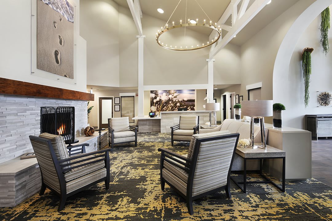 A modern hotel lobby featuring comfortable seating, a warm fireplace, and elegant lighting fixtures.