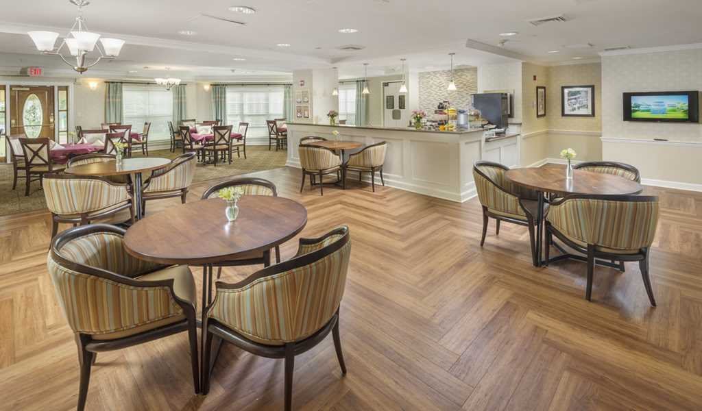 A modern dining area with wooden flooring, stylish tables and chairs, and ample lighting.