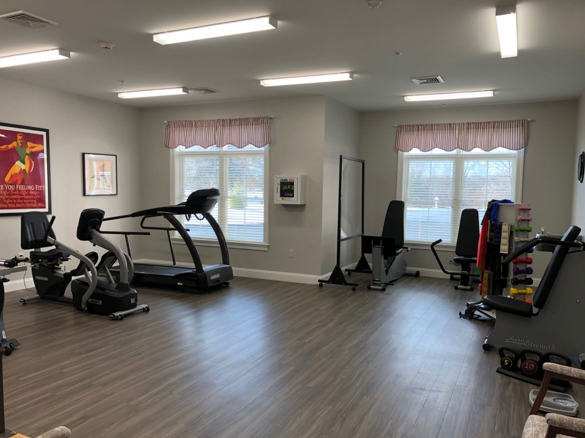 A well-lit gym with various fitness equipment including a treadmill and exercise bike.