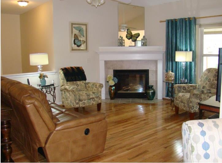 A cozy living room featuring comfortable armchairs, a fireplace, and wooden flooring.