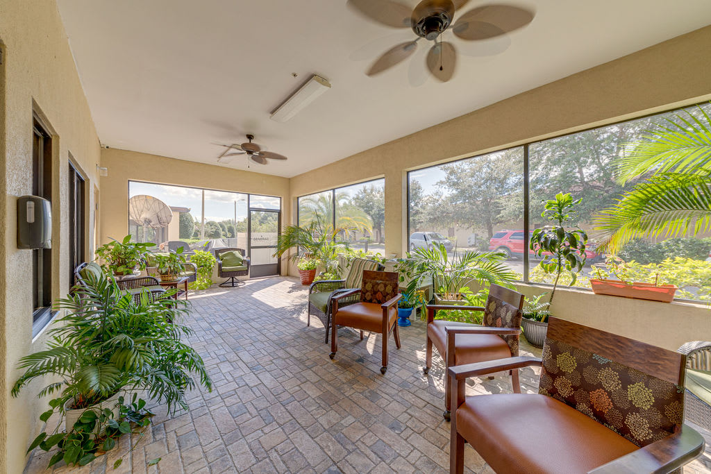 A bright sunroom with large windows, indoor plants, and comfortable seating.