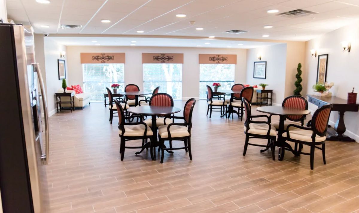 A bright and spacious dining area with multiple tables and chairs, featuring large windows.