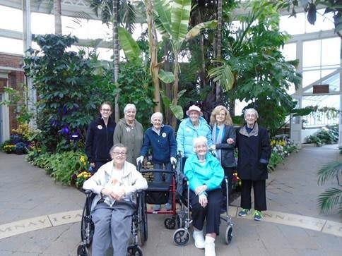 A group of people in a conservatory surrounded by lush greenery.