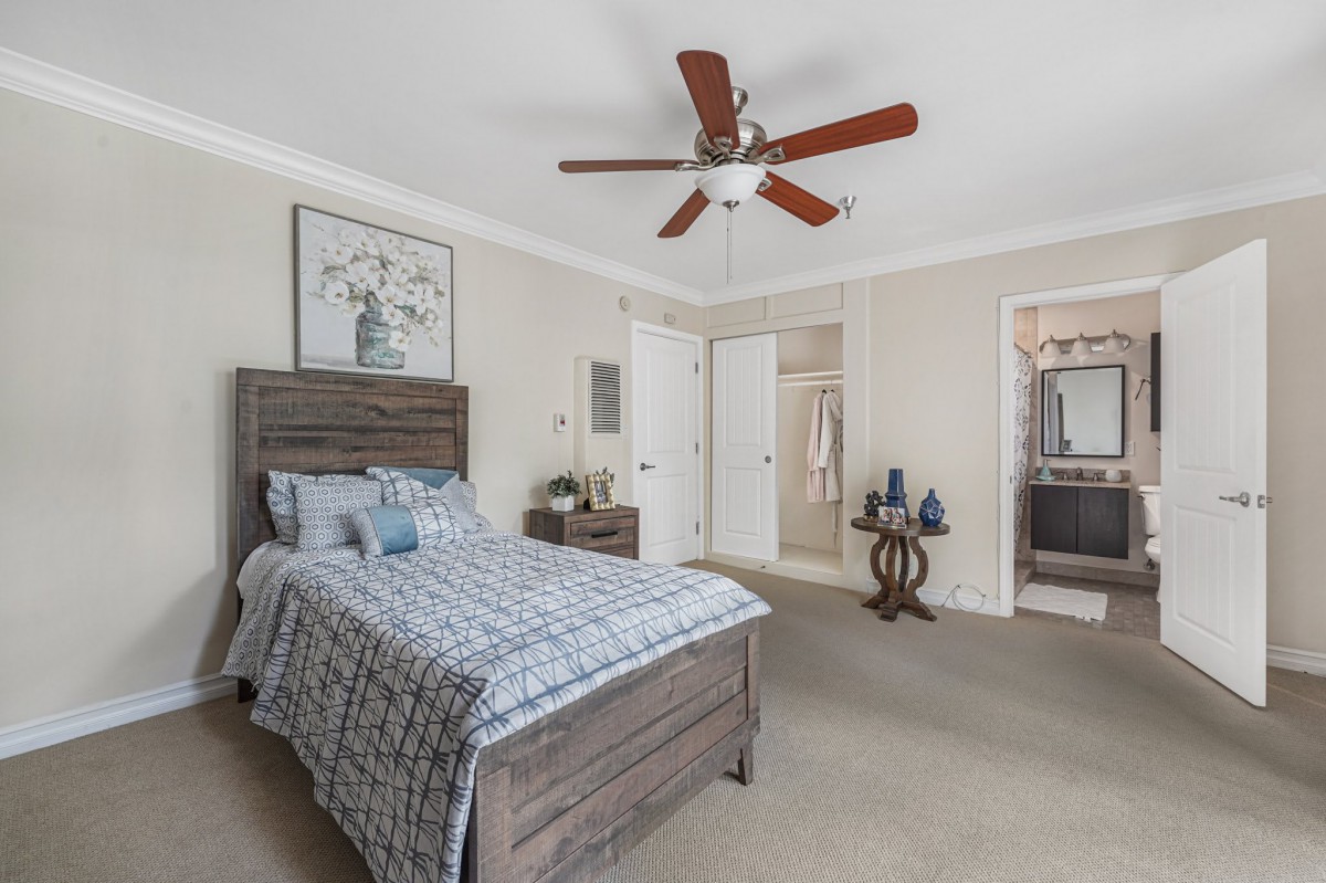 A cozy bedroom with a wooden bed, ceiling fan, and modern decor.