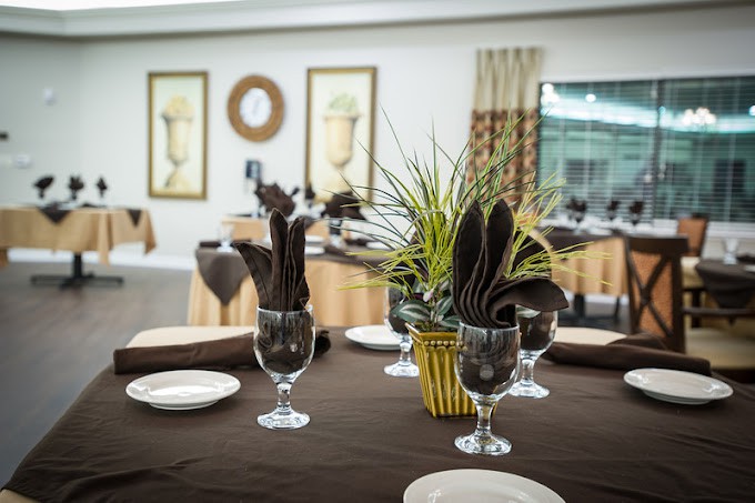 An elegantly set dining table with glassware and a plant centerpiece in a stylish restaurant.