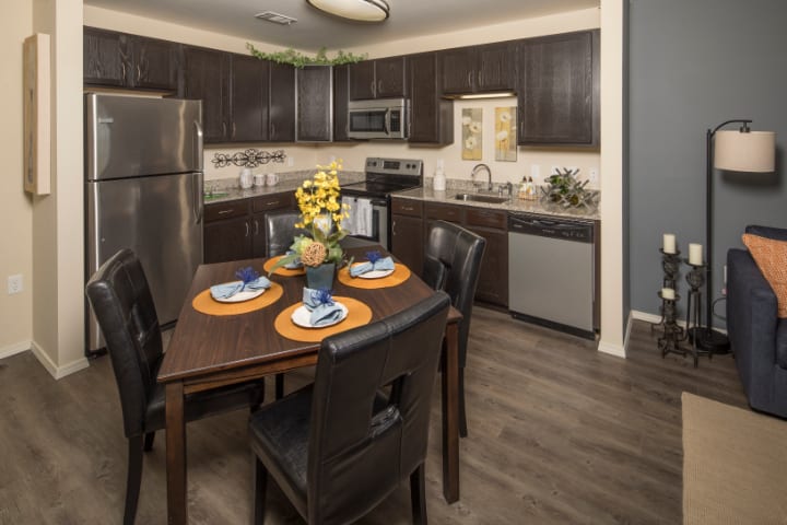 A modern kitchen and dining area featuring stainless steel appliances and a neatly set table.