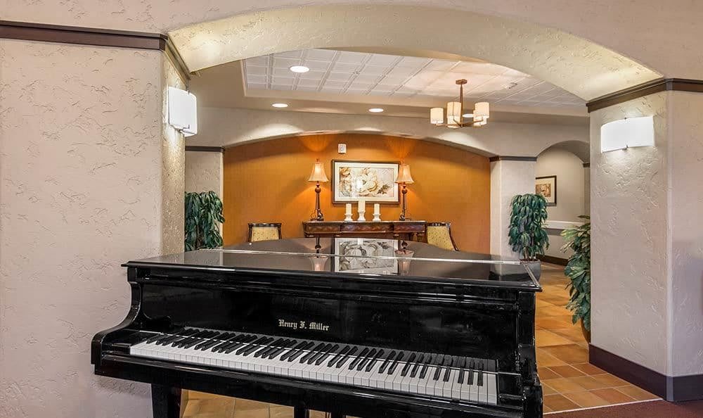 A grand piano in a warmly decorated lobby area with elegant lighting and artwork.