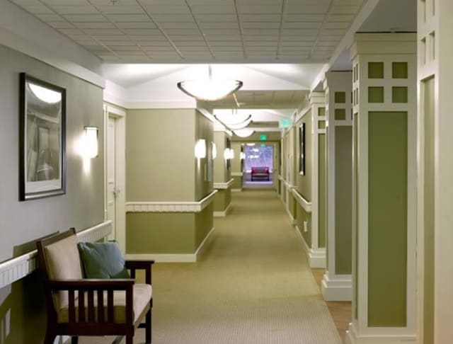 A well-lit hallway with seating and soft green walls.