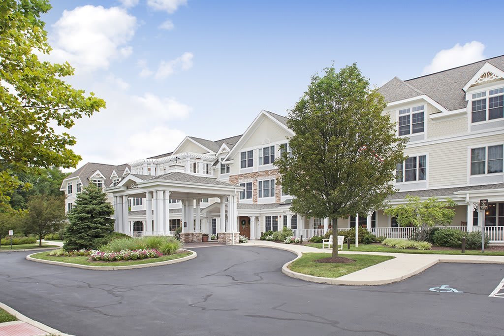 A view of a large, elegant residential building with landscaped surroundings and a circular driveway.