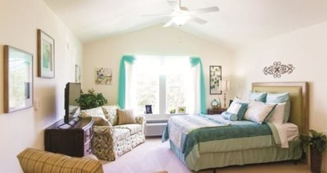 A cozy and well-decorated bedroom with a large window, bed, and sofa.