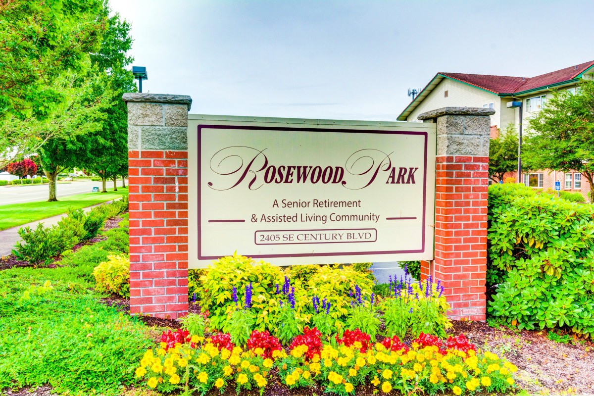 Entrance sign for Rosewood Park, surrounded by colorful flowers.