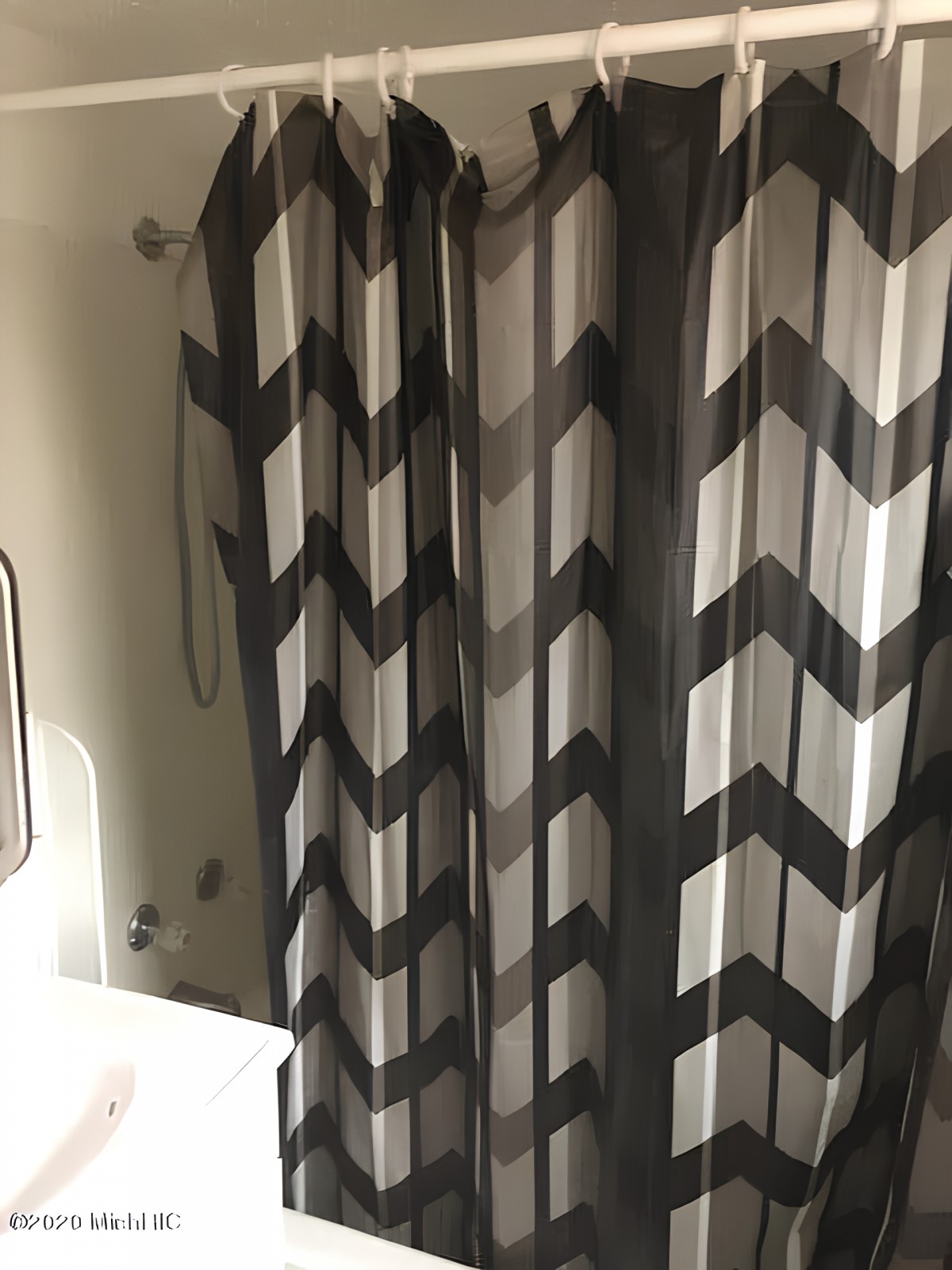 A bathroom with a chevron-patterned shower curtain.