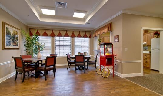 A cozy dining area with wooden tables and chairs, featuring a popcorn machine by the window.