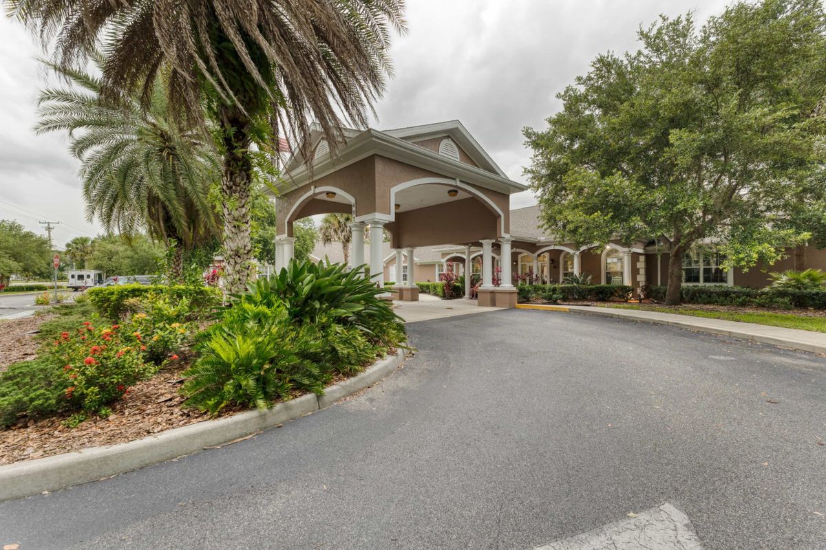 Entrance to a building with a landscaped driveway and surrounding trees.