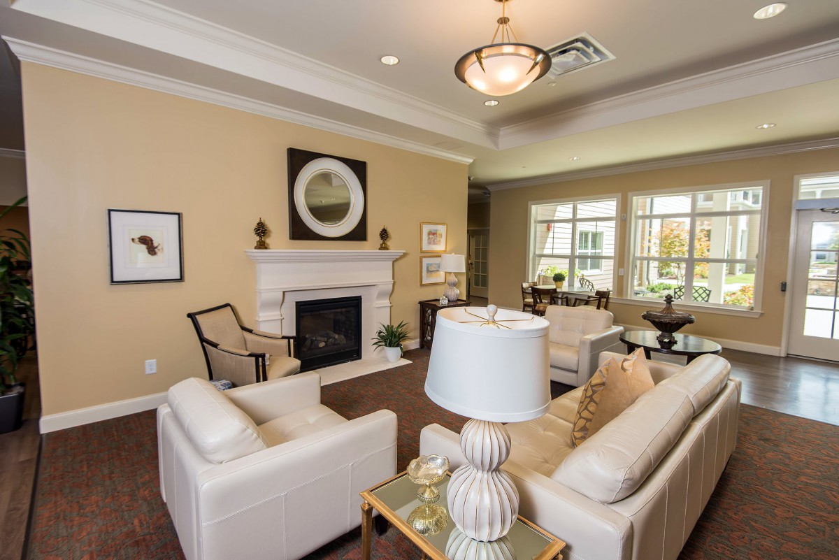 A cozy living room with cream-colored sofas, a fireplace, and elegant decor.