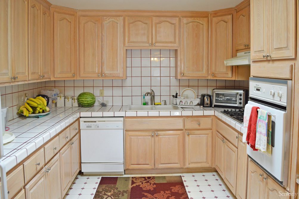 A spacious kitchen with wooden cabinets and tiled backsplash, featuring modern appliances.