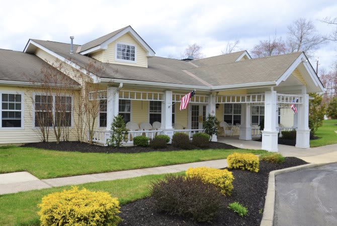 A charming residential house with a spacious porch and well-maintained garden, featuring an American flag.