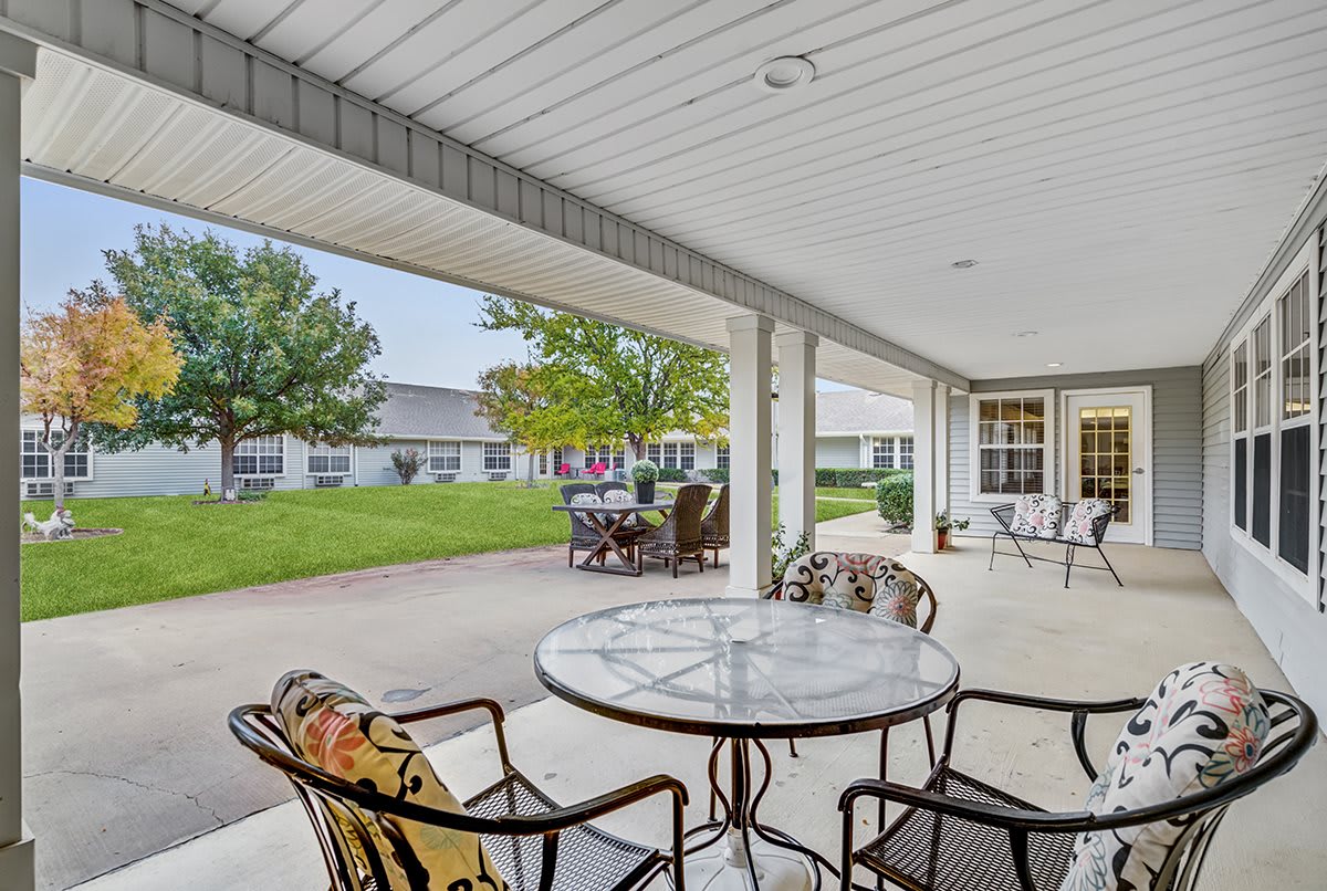A cozy outdoor patio area with seating, overlooking a landscaped yard.