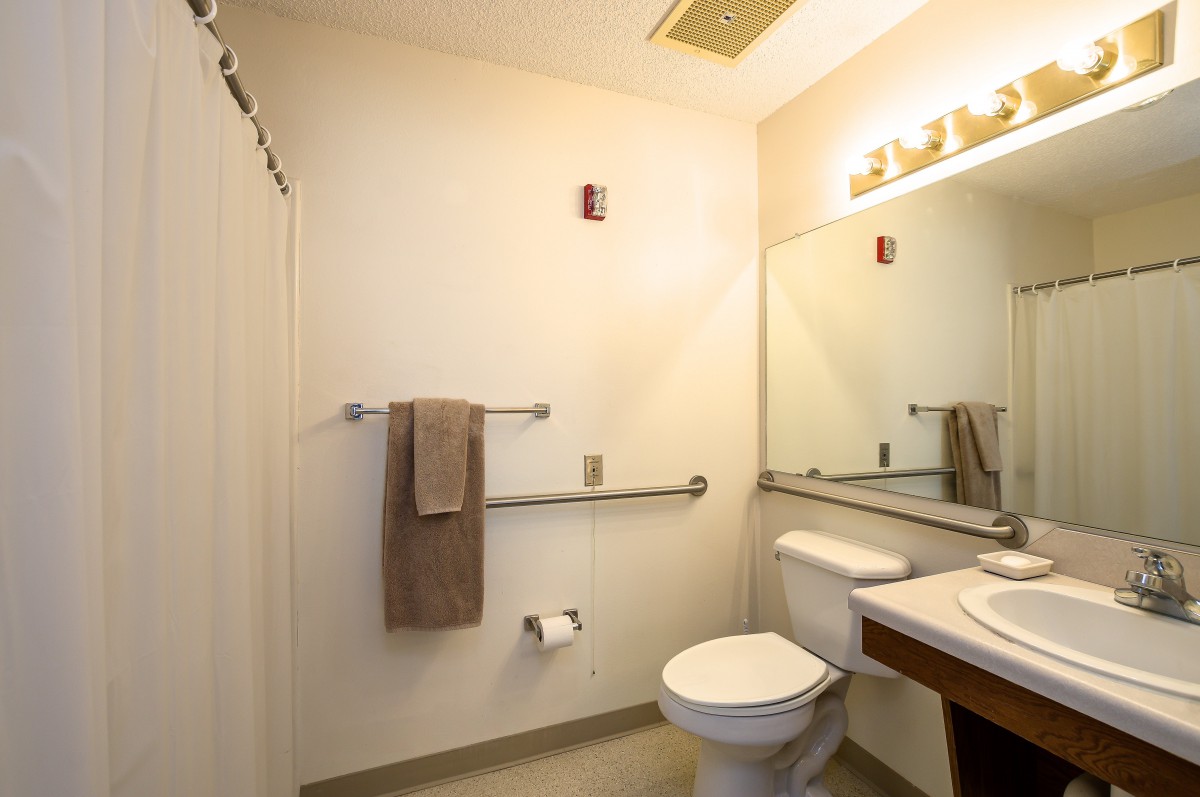 A clean and simple bathroom with a toilet, sink, mirror, and towel rack.