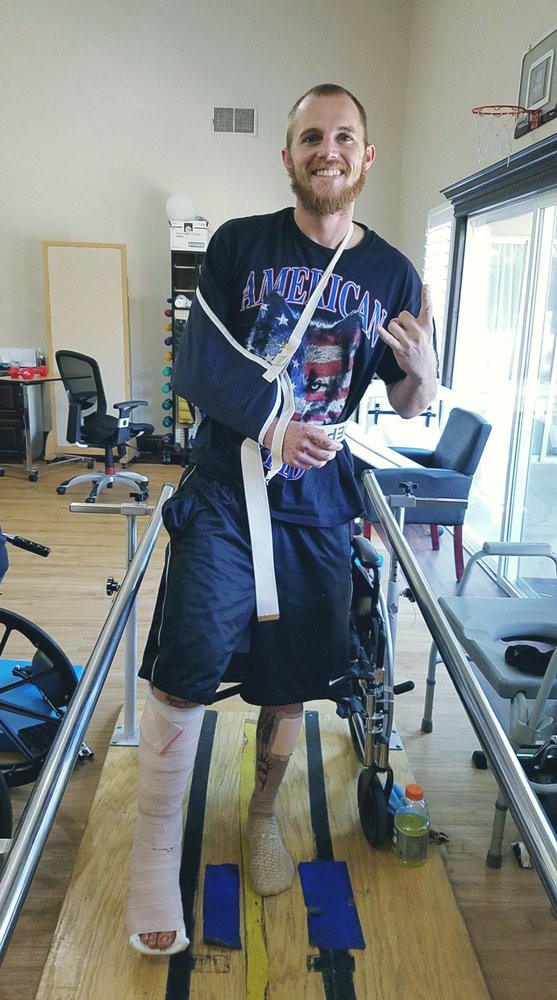 A person undergoing physical rehabilitation, using parallel bars and an arm sling.