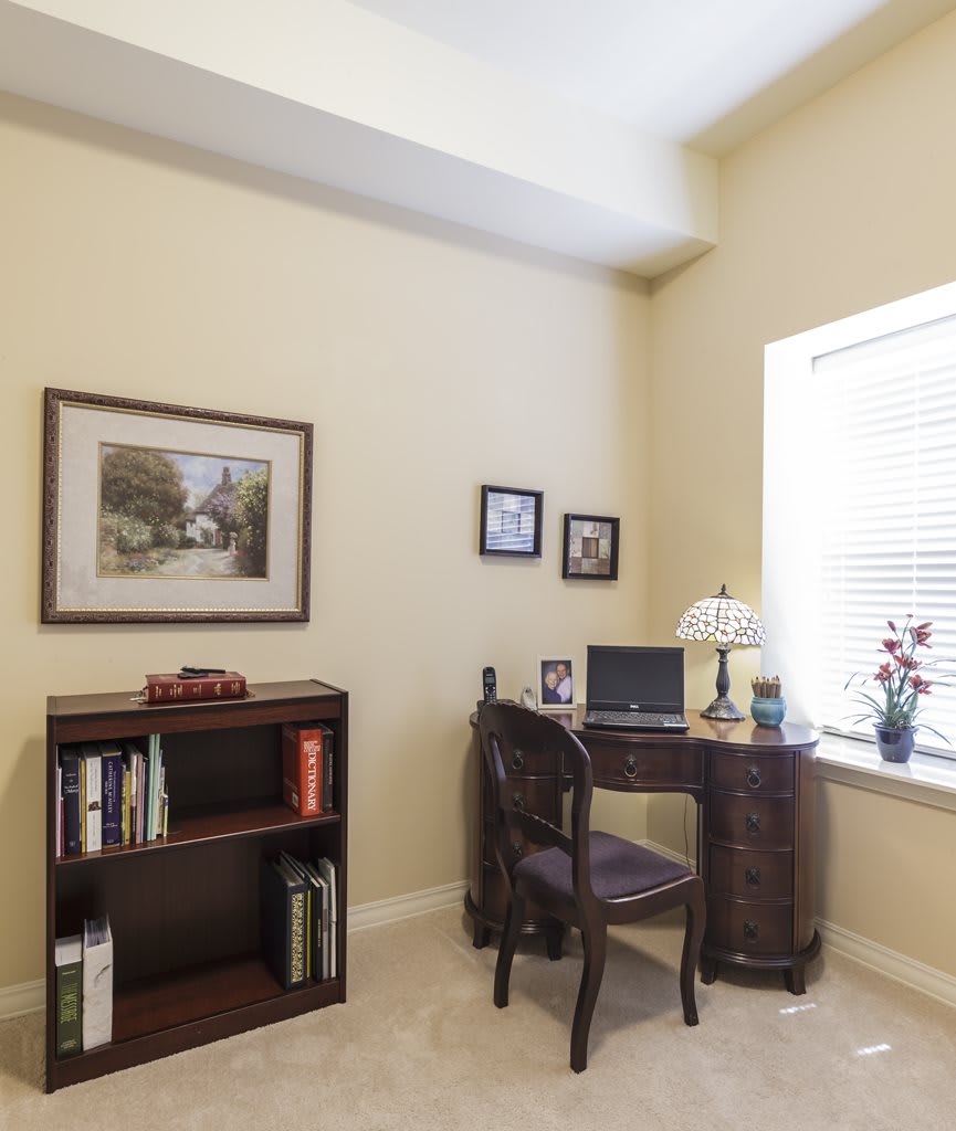A cozy home office with a wooden desk and a bookshelf.