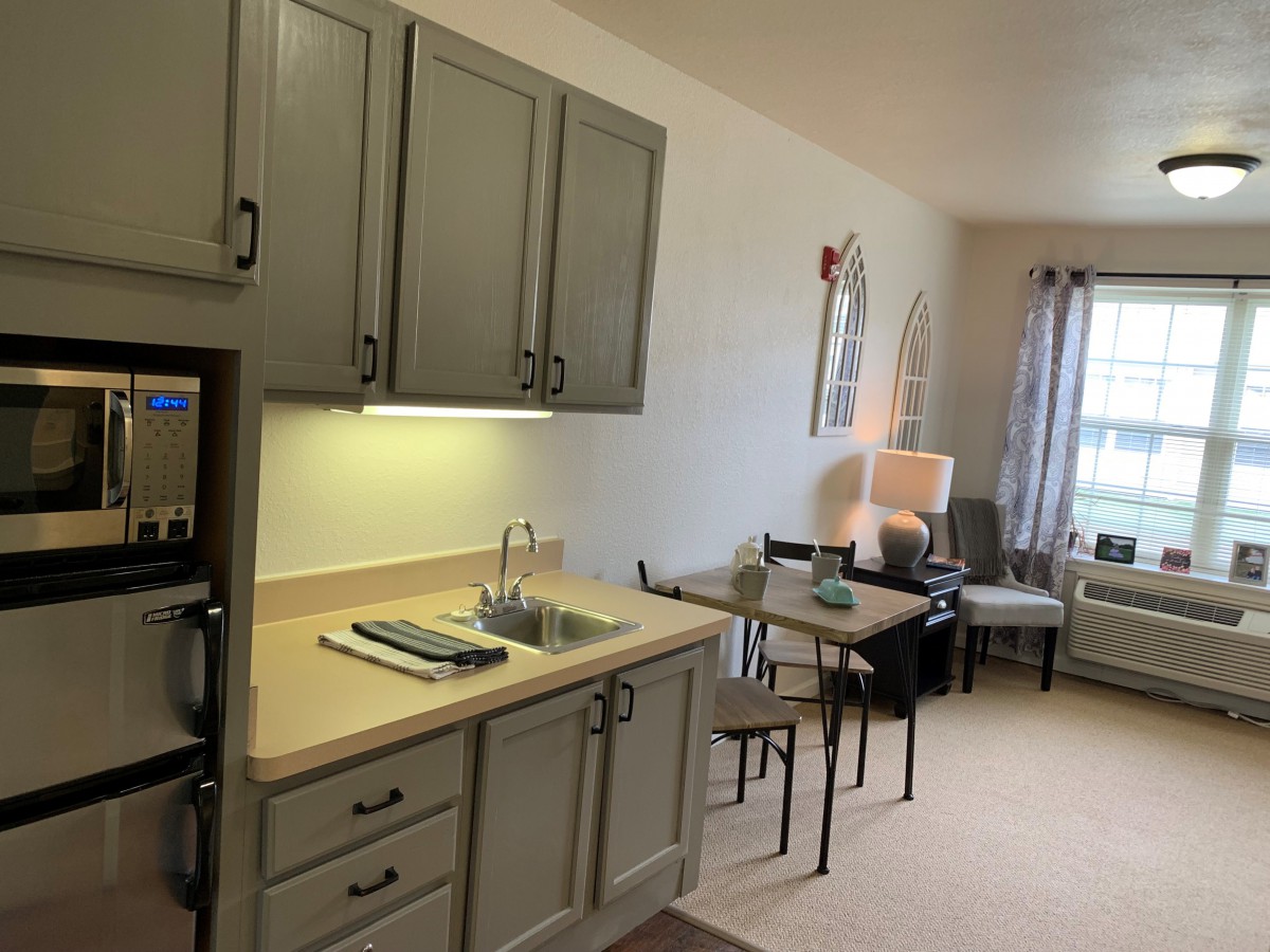 A cozy apartment interior featuring a small kitchen and living area with modern furniture.