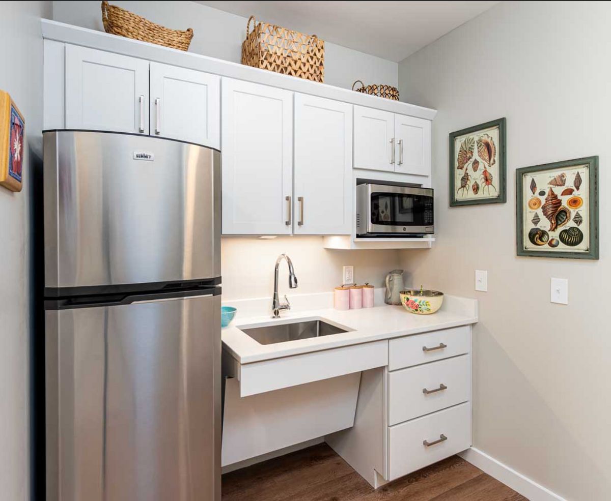 A modern kitchen with white cabinets, a stainless steel refrigerator, and decorative wall art.
