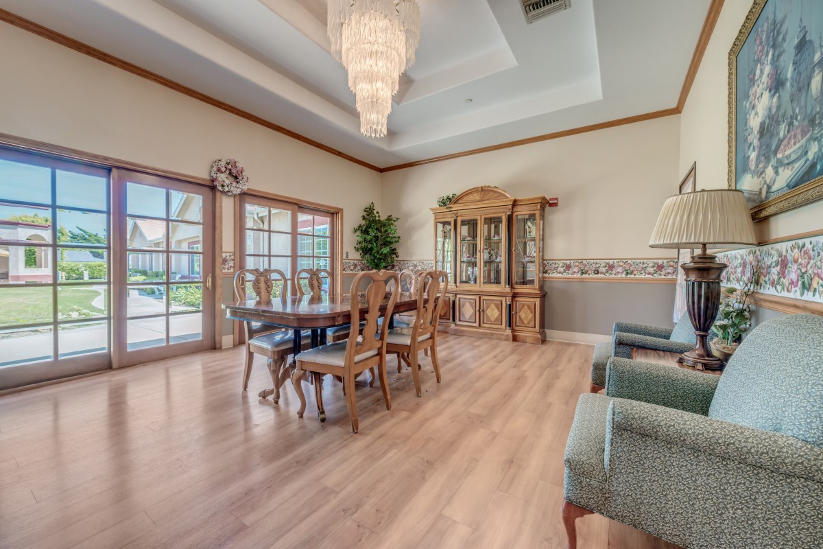 An elegantly designed dining room with a large chandelier, wooden flooring, and classic furniture.