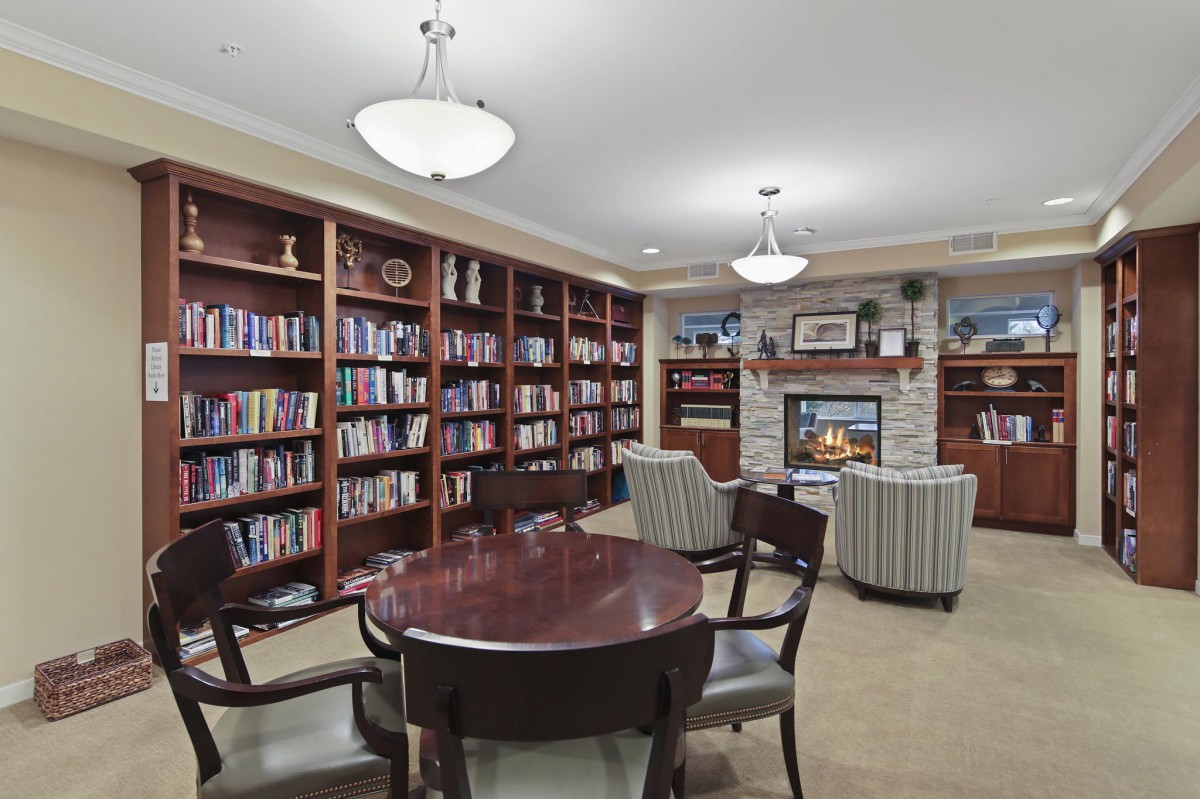 Cozy library with bookshelves, a fireplace, and seating area.