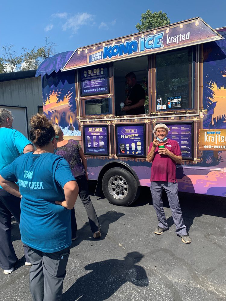 A group of people gather around a colorful food truck on a sunny day.