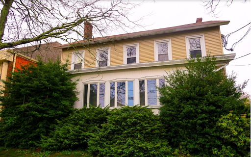A charming two-story house surrounded by lush greenery.