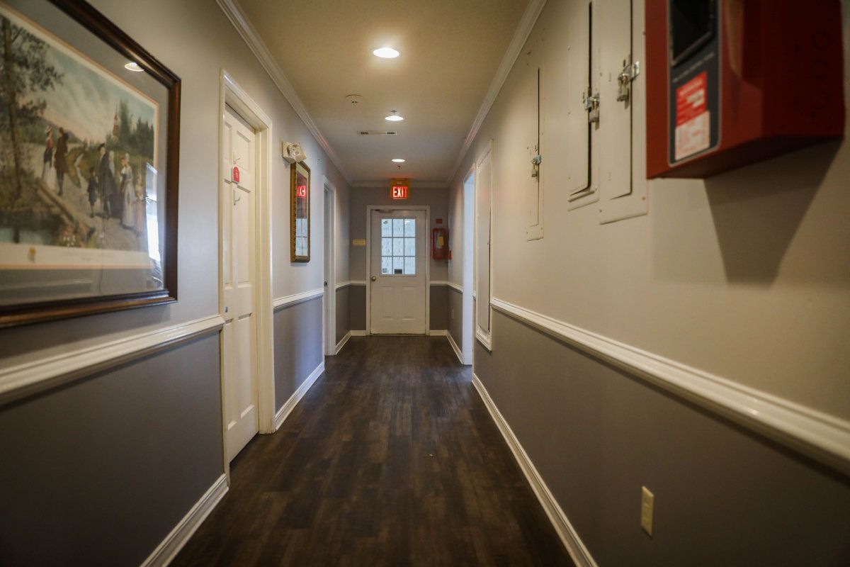 A well-lit indoor hallway with doors and dark flooring.