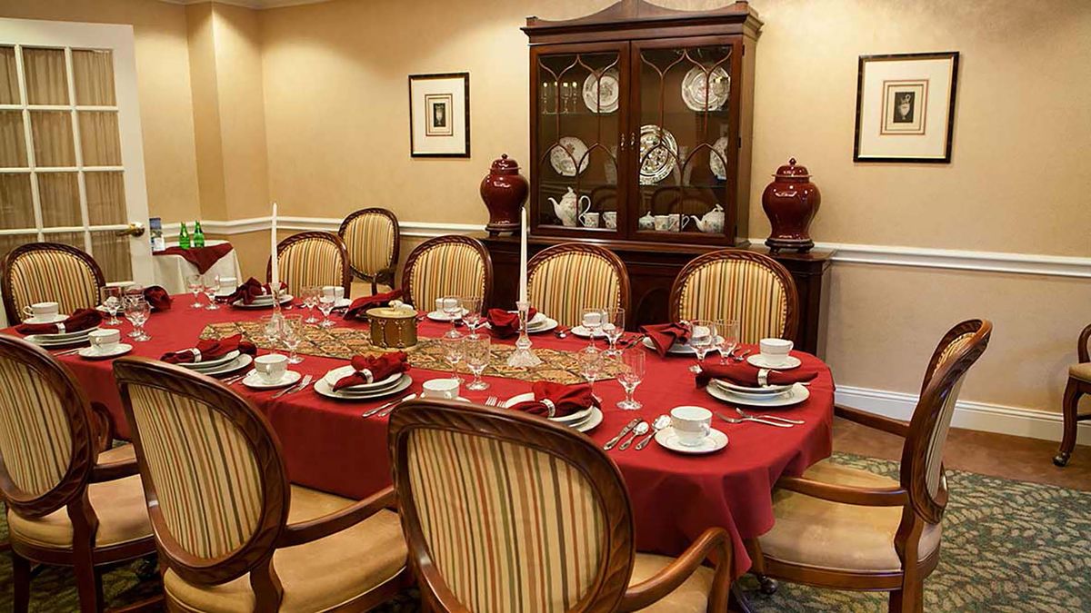A formal dining room with a red tablecloth and elegant place settings.