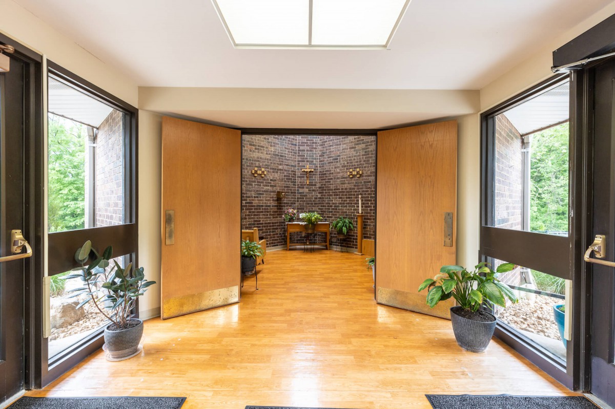 A modern entrance with wooden doors, indoor plants, and a tiled wall.