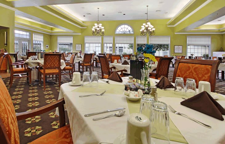 A well-decorated dining room with set tables and elegant chandeliers.