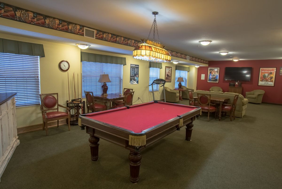 A cozy recreation room featuring a red-felt pool table and comfortable seating.