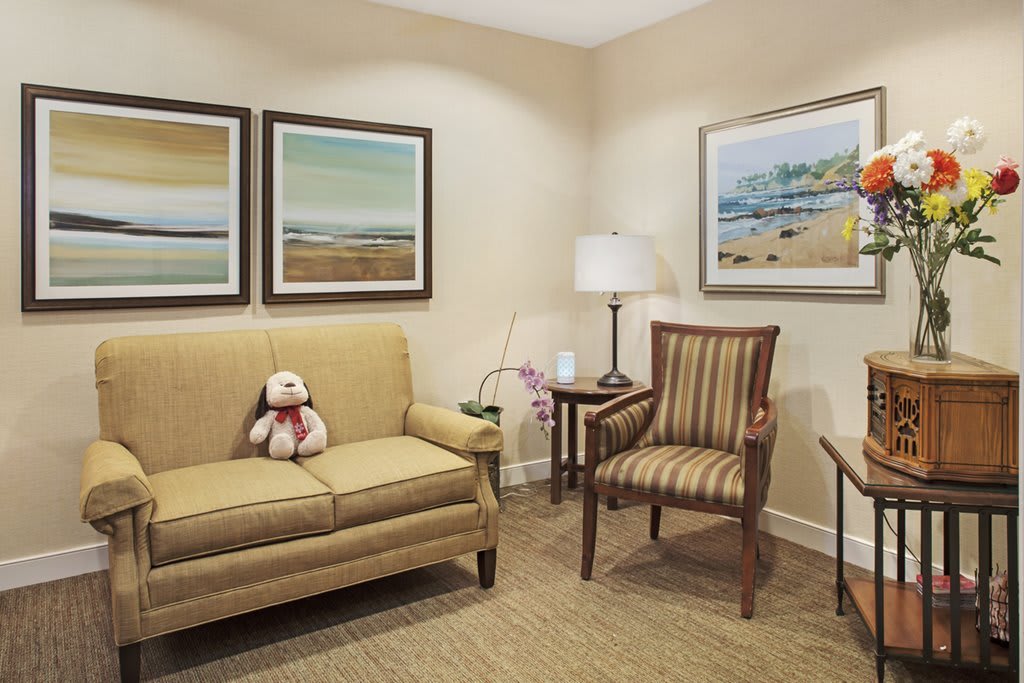 A cozy living room with a sofa, armchair, and decorative paintings.