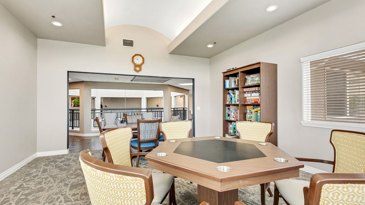 A cozy game room with a hexagonal table and bookshelves filled with games.