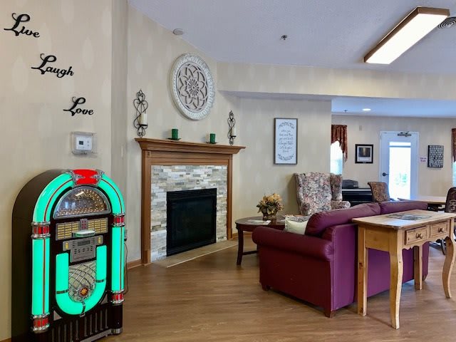 A cozy living room with a jukebox and a fireplace, featuring comfortable seating and elegant decor.