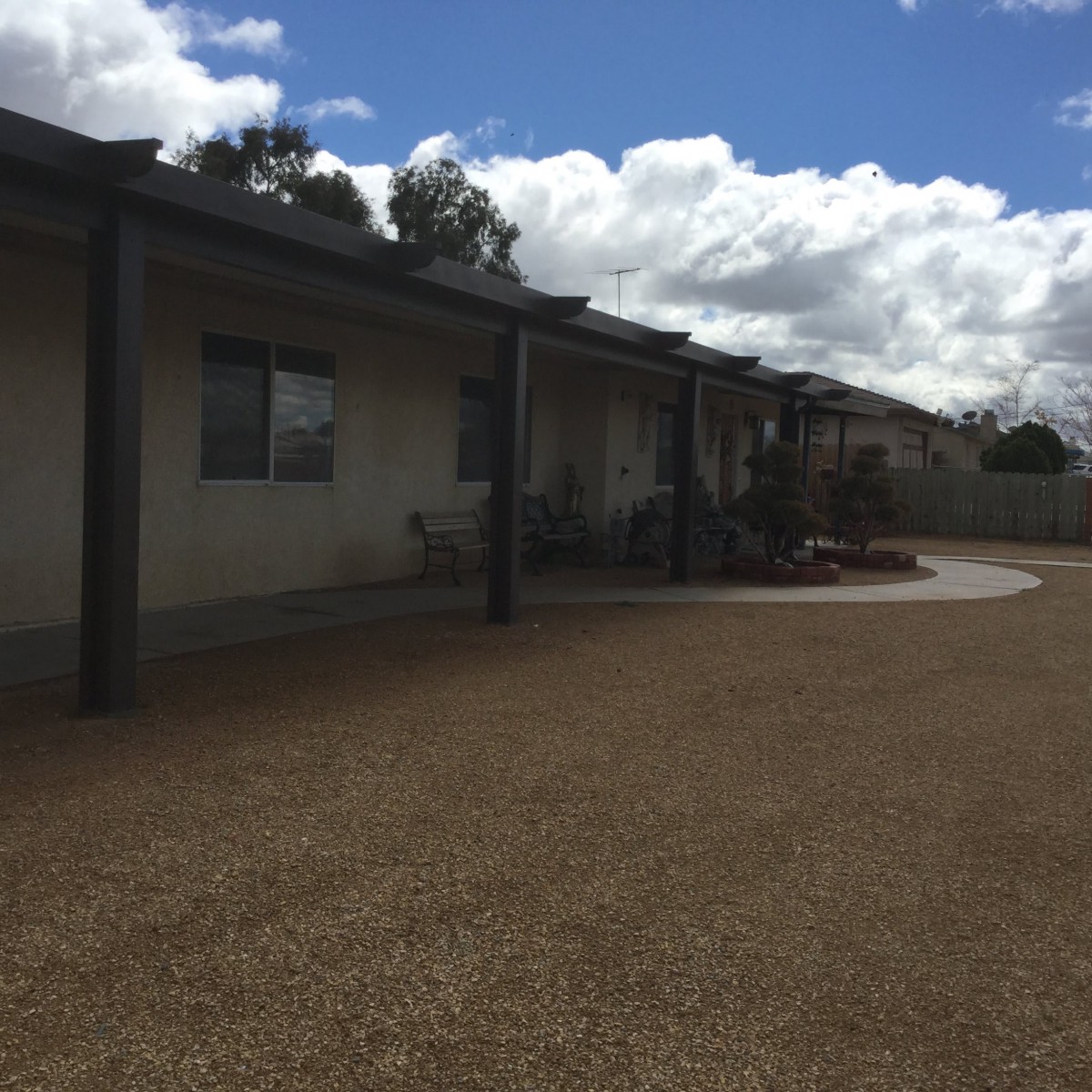 A single-story house under a cloudy sky with a gravel driveway.