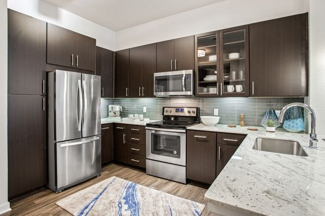 A modern kitchen with stainless steel appliances and dark cabinetry.