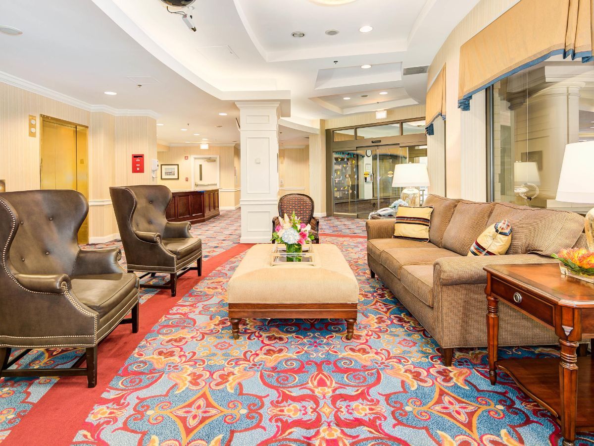 A cozy hotel lobby with comfortable seating and colorful carpet.