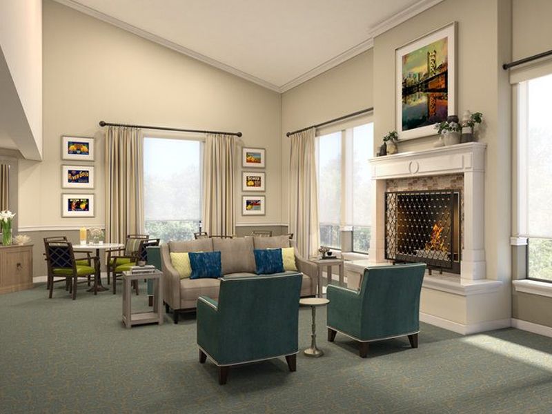 A modern living room with a comfortable seating arrangement, featuring a sofa and two chairs near a fireplace, decorated with artwork and soft lighting.