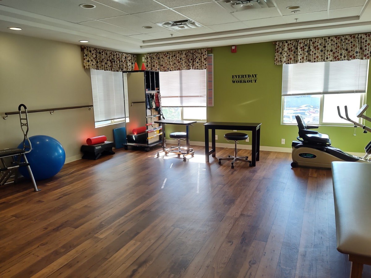 A bright exercise room equipped with therapy gear and yoga balls.