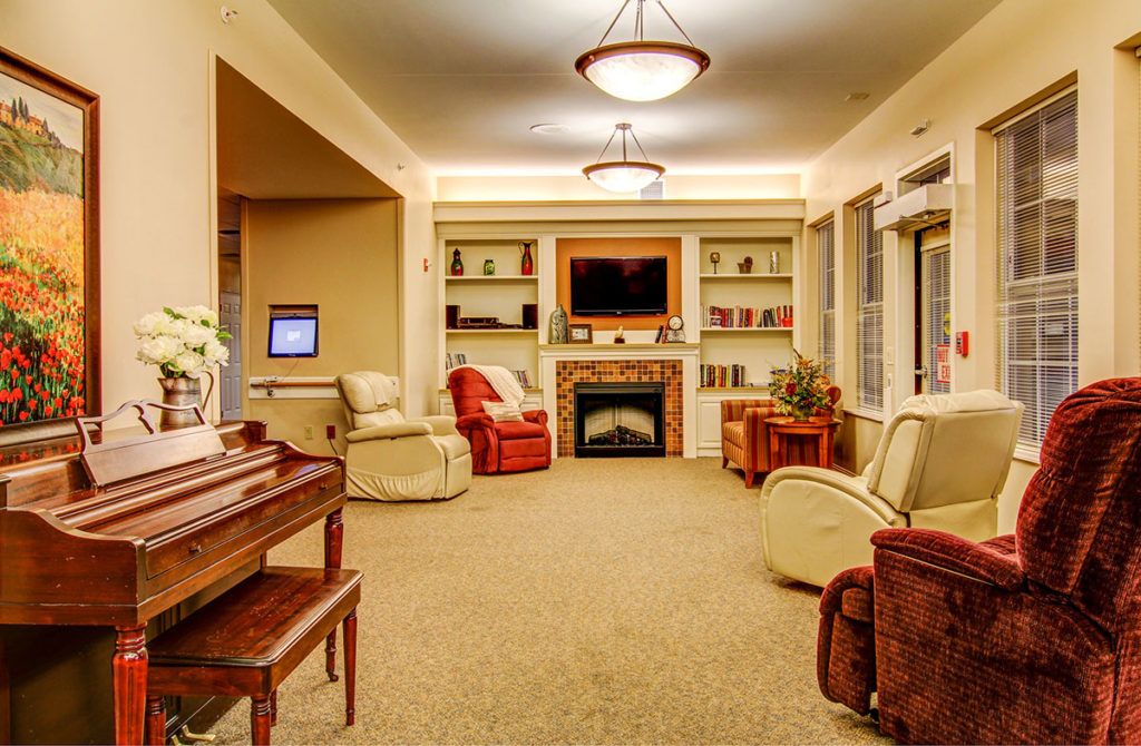 A cozy living room featuring a fireplace, television, and comfortable armchairs.