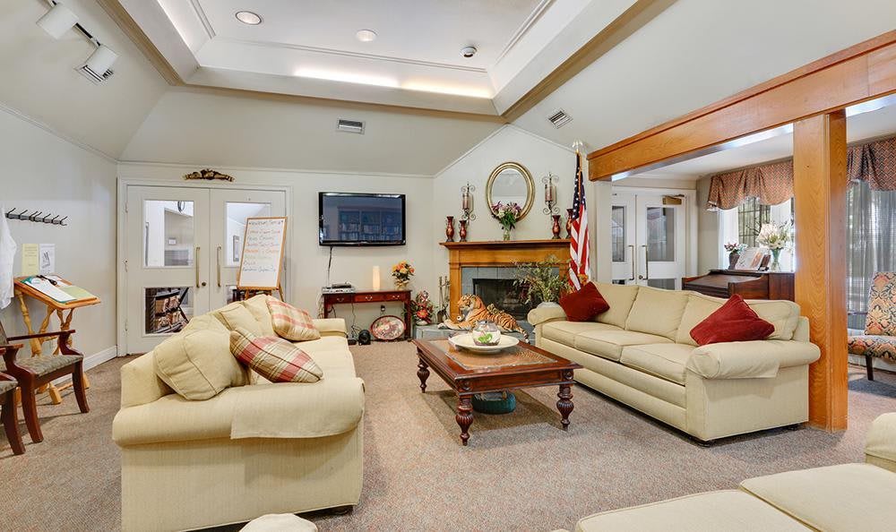 A cozy living room featuring comfortable sofas, a television mounted on the wall, and a fireplace adorned with decorative items.