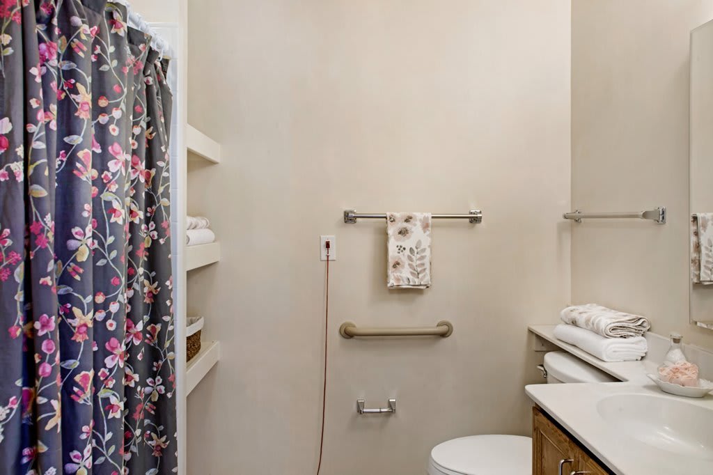 A small bathroom with a shower curtain, towel racks, and storage shelves.