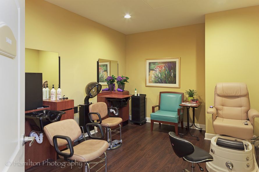 A cozy salon interior featuring multiple styling stations, mirrors, and a comfortable seating area.