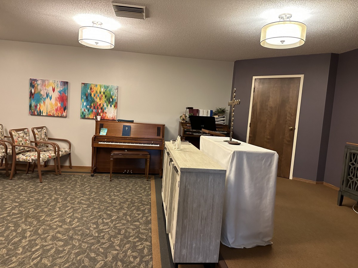 A cozy waiting room with a piano, artwork, and a reception desk.